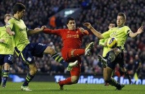 Liverpool's Suarez is challenged by Aston Villa's Lichaj and Baker during their English Premier League soccer match at Anfield in Liverpool